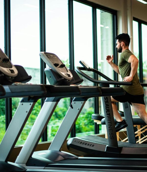 Man performing a controlled strength exercise in a modern gym with mint color accents.