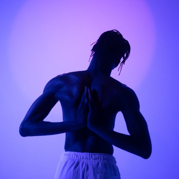 Silhouette of a man stretching against a sunrise, representing wellbeing and peace.